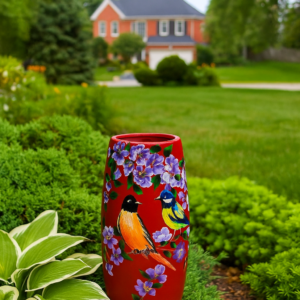 Hand-painted decorative vase featuring colourful songbirds and purple flowers on a red background