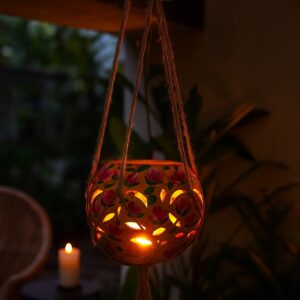 Handcrafted terracotta hanging lantern illuminated by a tea light candle with decorative cut-out pattern