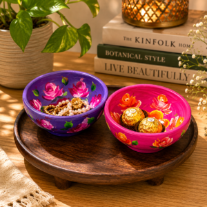 Hand-painted floral terracotta trinket bowls in pink and purple displayed on a wooden tray